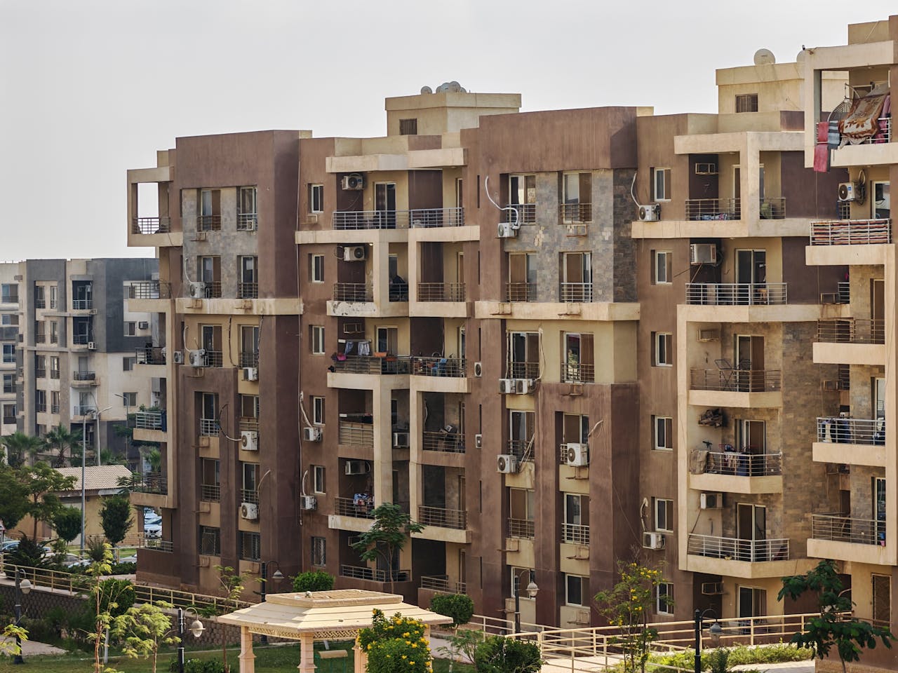Modern apartment buildings with balconies and lush greenery in urban setting.